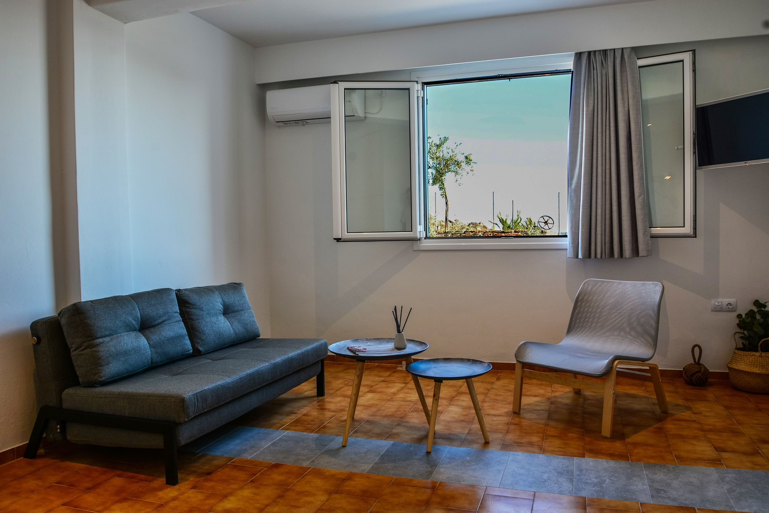 A modern living room with a grey sofa, a small round table, and a chair.