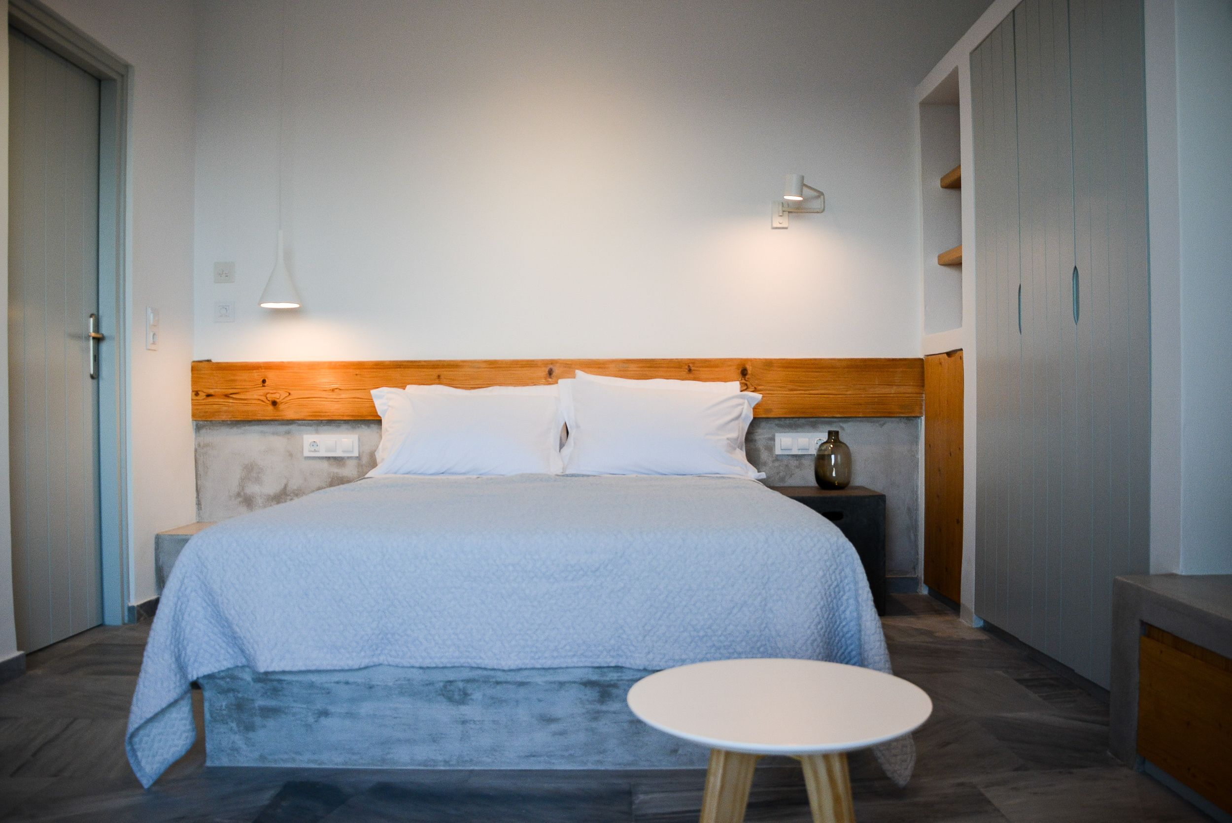 A bedroom with a bed, bedside table, and a small round table.