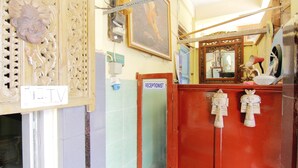 Un área de recepción con un televisor, letrero de recepcionista, un espejo y elementos decorativos.