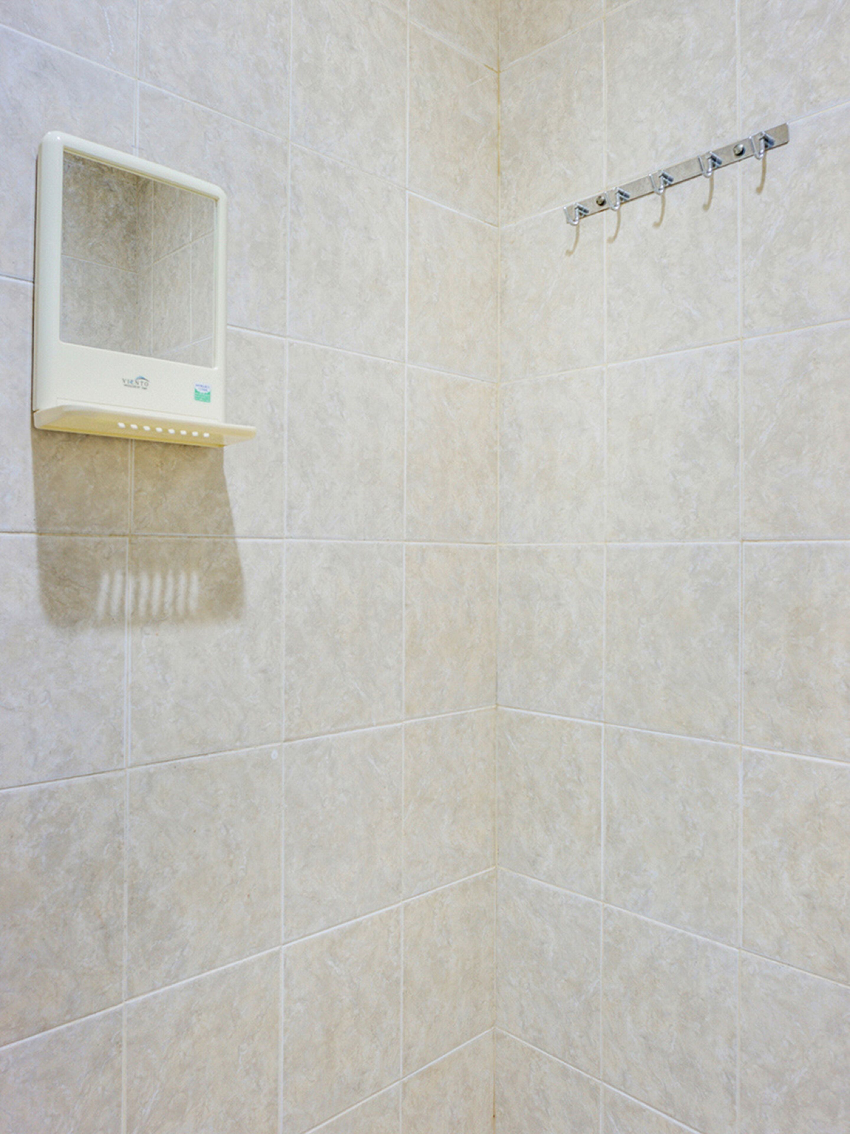 Un baño con azulejos color beige, un box de ducha blanco y un perchero.