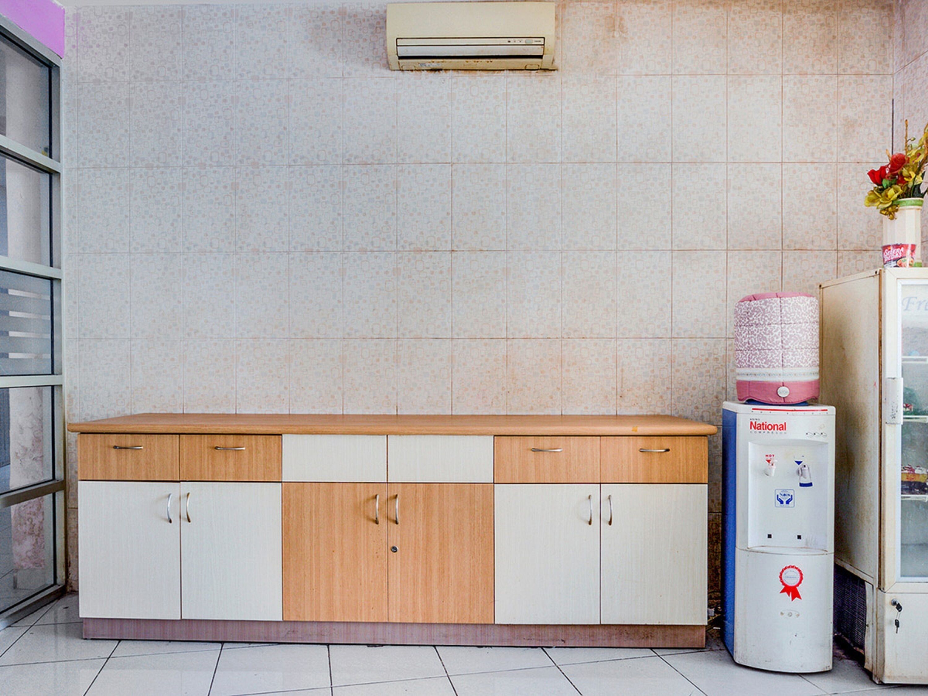 A kitchen with a wooden countertop, white cabinets, a water dispenser, and a tiled backsplash.