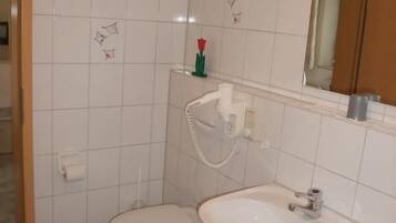 Uma casa de banho com sanita, lavatório e espelho.