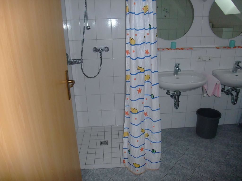 Un baño con ducha, dos lavamanos, un espejo y una cortina.