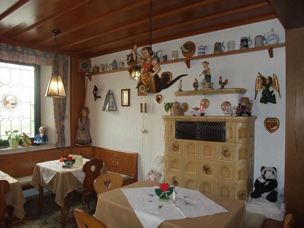 Un comedor acogedor con mesas y sillas de madera, una pared decorativa con varios objetos, y una ventana con vistas.