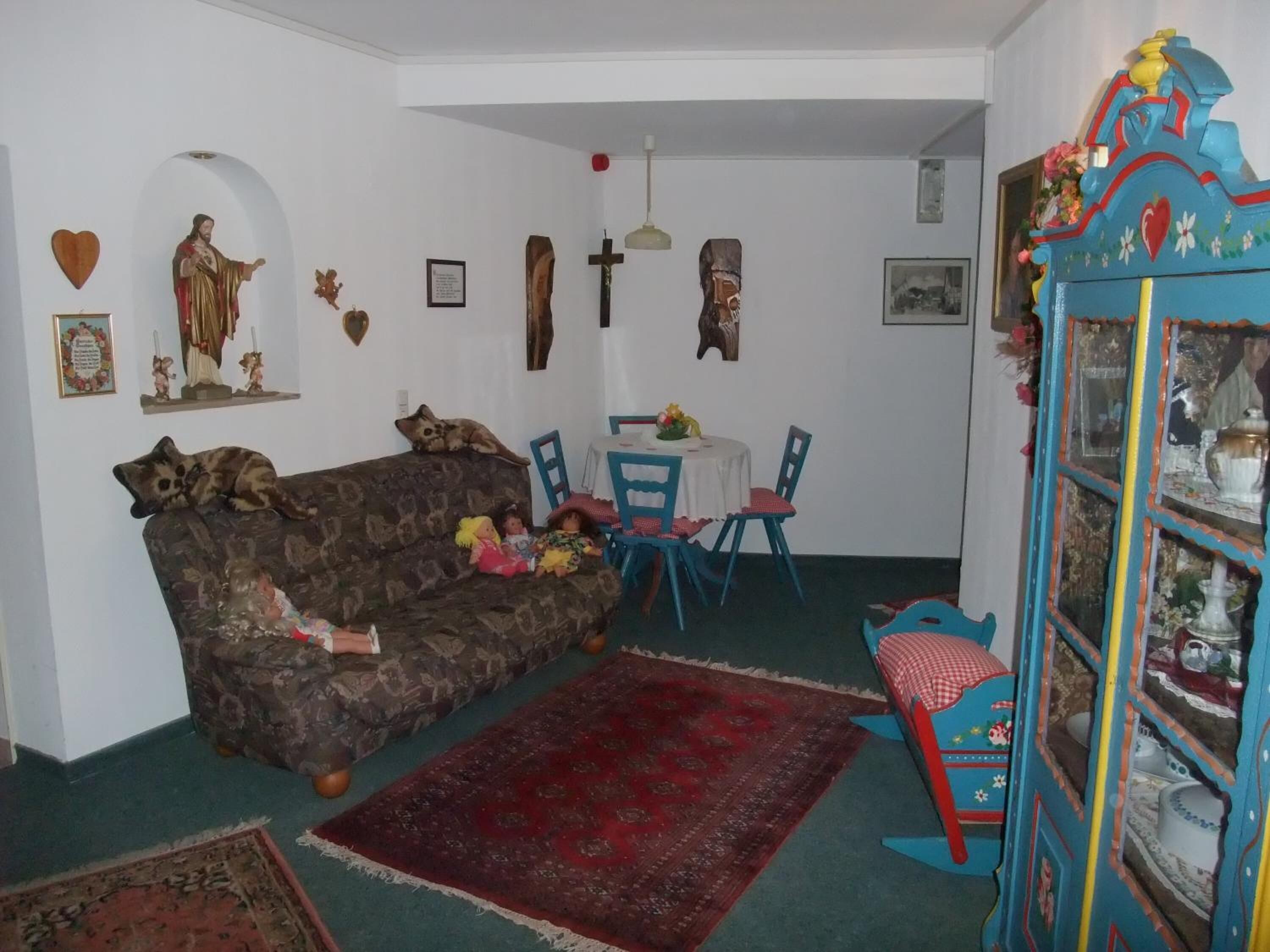 Ein gemütliches Wohnzimmer mit einer Couch, Sesseln, einem Esstisch und einem dekorativen Schrank.