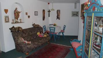 Ein gemütliches Wohnzimmer mit einer Couch, Sesseln, einem Esstisch und einem dekorativen Schrank.