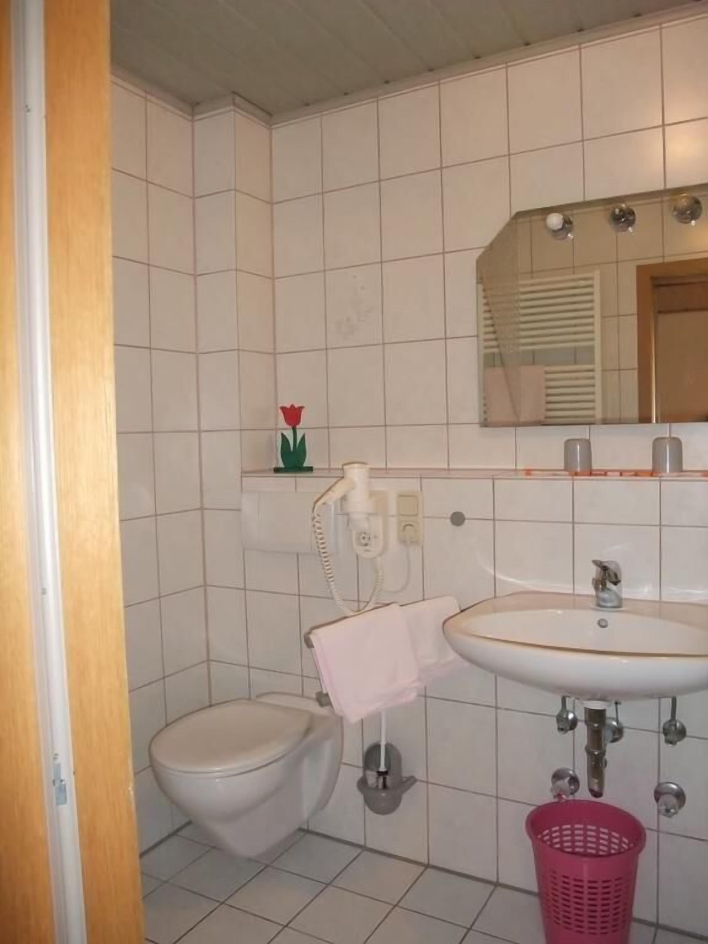 Un baño con inodoro, lavabo y espejo sobre él.