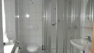 A bathroom with a shower enclosure, toilet, and sink.