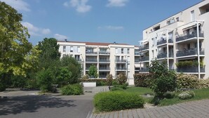A modern apartment building with multiple balconies, a paved driveway, and surrounding greenery. - Large apartment T2, quiet, near Lyon, balcony parking and transport (Saint-Priest)