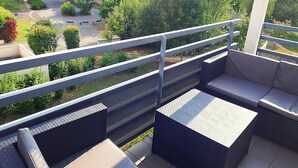 A balcony with outdoor seating, a view of a parking area, and surrounding greenery. - Large apartment T2, quiet, near Lyon, balcony parking and transport (Saint-Priest)