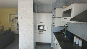 A compact kitchen with white cabinetry, a built-in microwave, and a black countertop. - Large apartment T2, quiet, near Lyon, balcony parking and transport (Saint-Priest)