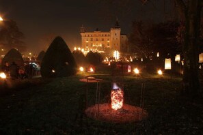 A castle-like building with a moat and a fire pit in the foreground.