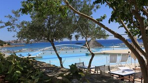 A pool area with lounge chairs and a view of the sea. - Blu Acqua (Agios Nikolaos)
