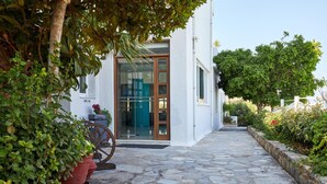 A stone-paved pathway leading to a white building with a glass door and windows. - Blu Acqua (Agios Nikolaos)