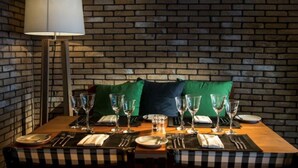 A dining table set with glasses and cutlery, a lamp, and a brick wall background. - Blu Acqua (Agios Nikolaos)