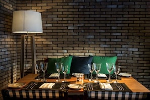 A dining table set with glasses and cutlery, a lamp, and a brick wall background. - Blu Acqua (Agios Nikolaos)