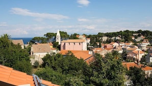 En kystby med bygninger med terracotta tag, en markant kirke og frit udsyn til havet.