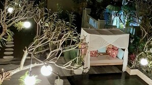 A nighttime outdoor pool area with lounge chairs and a canopy. - Lin Ubud (Ubud)