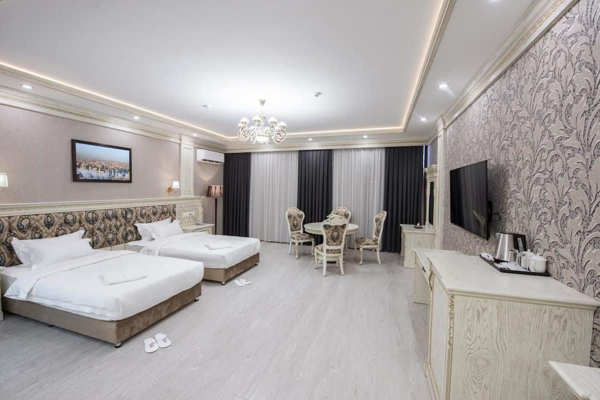 Quarto de hotel com duas camas, área de refeições, televisão e minibar.