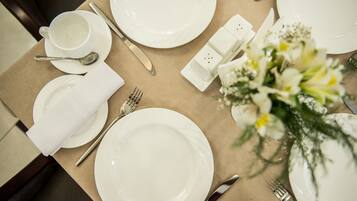 A table set with white plates, silverware, a cup, and a salt and pepper shaker.