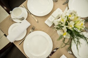 Une table dressée avec de l’assiette blanche, des couverts en argent, une tasse et un salière et un poivrière.