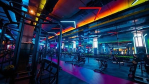 A gym with various exercise equipment and neon lighting. - Simma Hotel spa and waterpark (Tashkent)