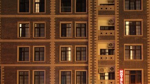 A multi-story hotel building with a brick facade, multiple windows, and a neon sign indicating the name 'ZAMZAM HOTEL'. - ZamZam Hotel (Baku)