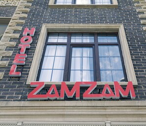 A hotel sign with the name "ZAMZAM" in large red letters on a stone building facade. - ZamZam Hotel (Baku)