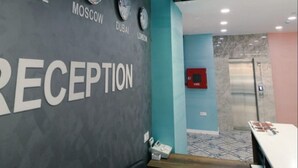 A reception area with a wall displaying clocks set to Moscow, Dubai, and London. - ZamZam Hotel (Baku)