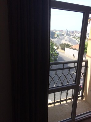 A view from a balcony with a metal railing, overlooking a cityscape with buildings and a road. - ZamZam Hotel (Baku)