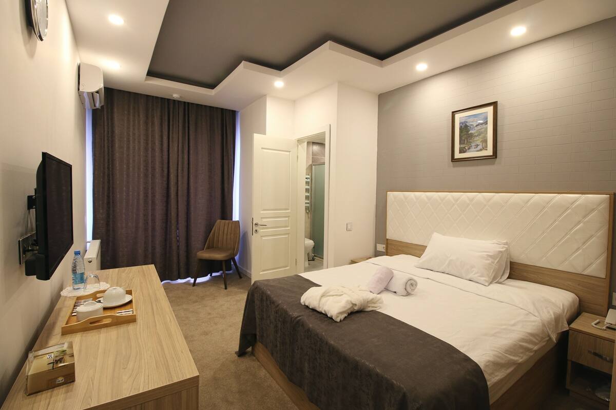 A hotel room with a bed, bedside table, and a television.