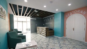 A hotel reception area with a reception desk, seating area, and a large door labeled "Restoran". - ZamZam Hotel (Baku)