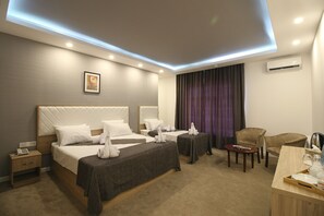 A hotel room with two beds, a desk, a chair, a nightstand, and an air conditioning unit. - ZamZam Hotel (Baku)