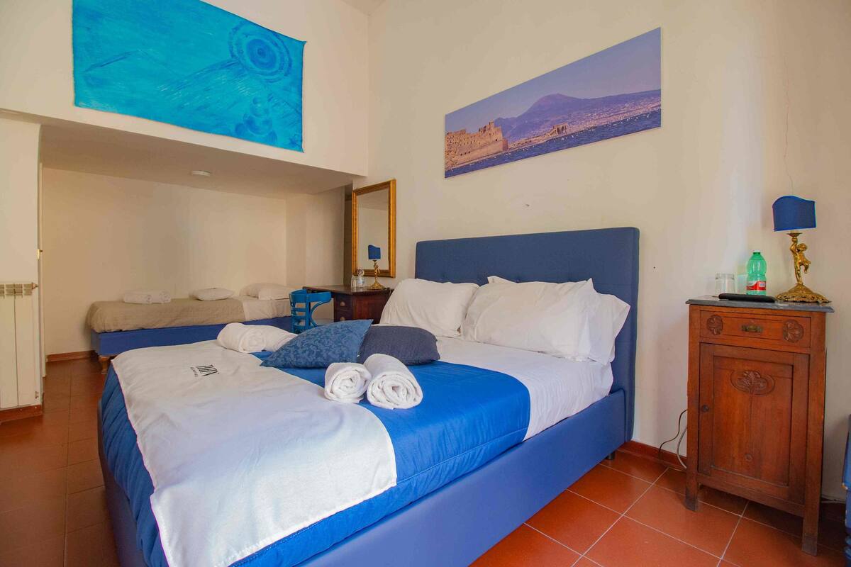 A hotel room with a large bed, a nightstand, a lamp, and a painting on the wall.