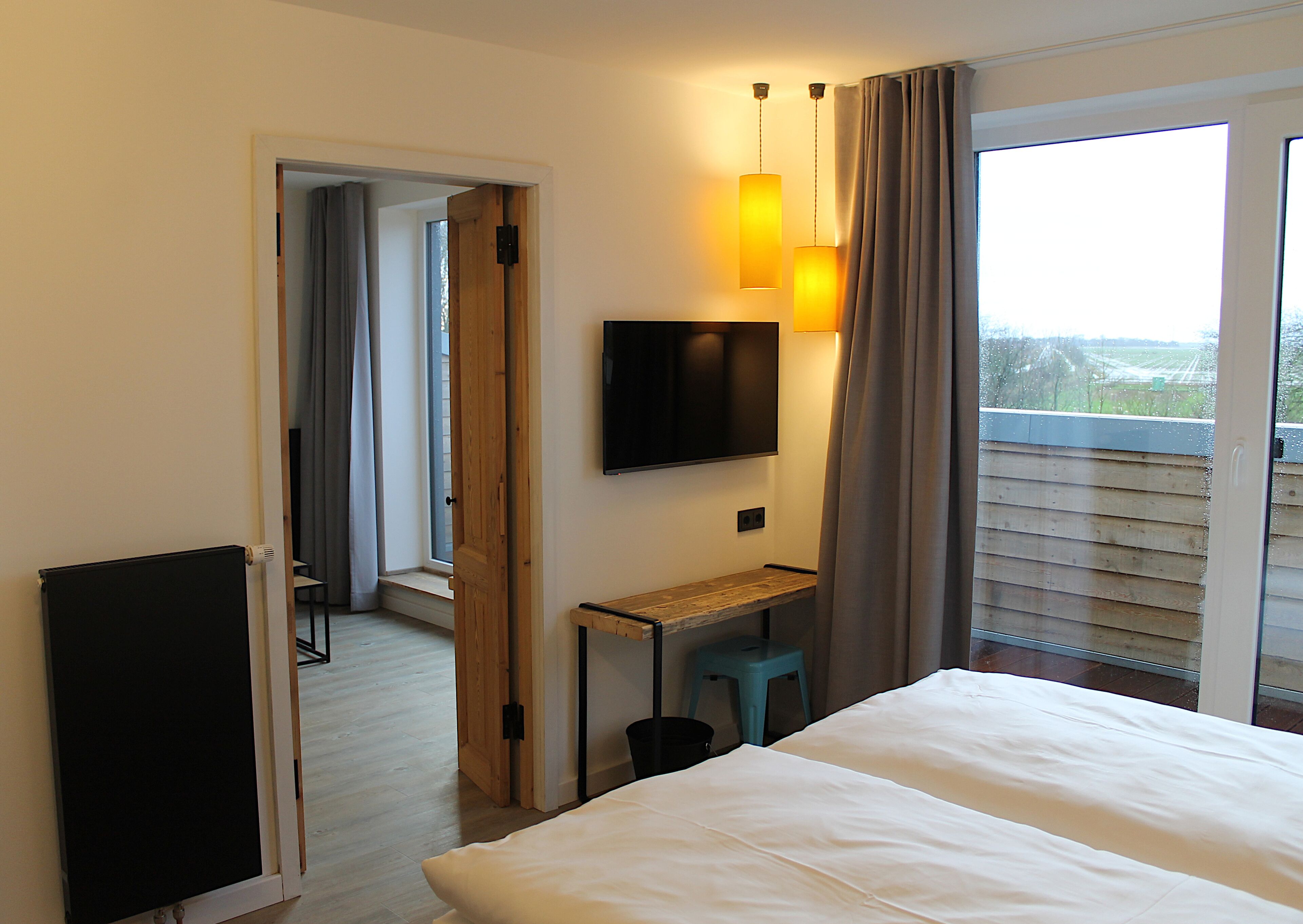 Ein Hotelzimmer mit Bett, Schreibtisch, Fernseher und einem Fenster mit Vorhängen.