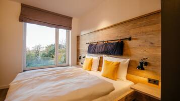 Un dormitorio con una cama grande, cabecera de madera y ventana con vistas a árboles.