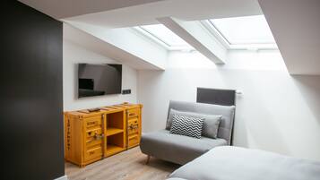 Un dormitorio moderno con tragaluces, una cama, un sofá y un mueble de almacenamiento de madera.