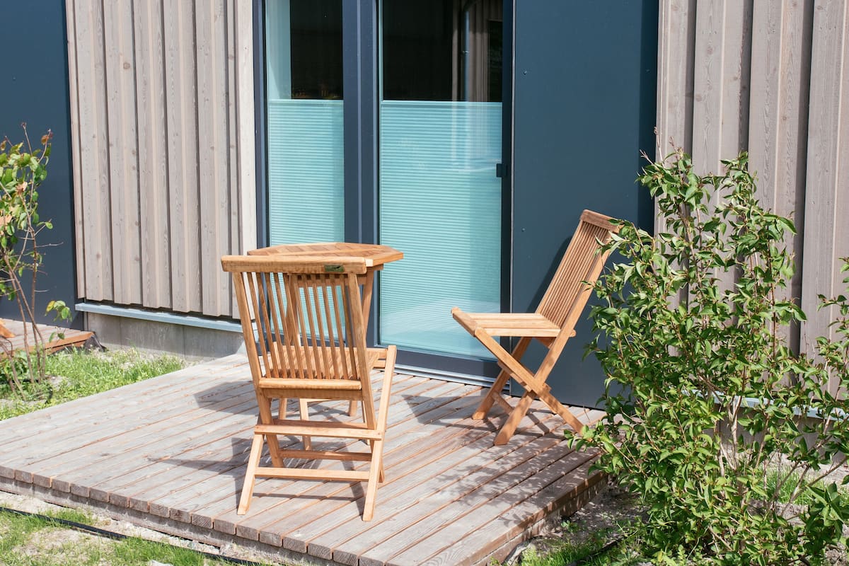 Une terrasse en bois avec deux chaises et une petite table.