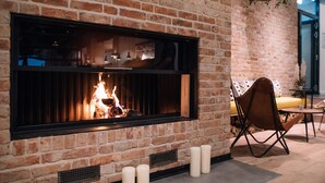 Una chimenea de ladrillo con fuego, un sofá amarillo y un sillón en un interior moderno.