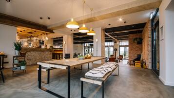 Una cocina amplia y moderna con una larga mesa de madera, luces colgantes y una pared de ladrillo decorativa.