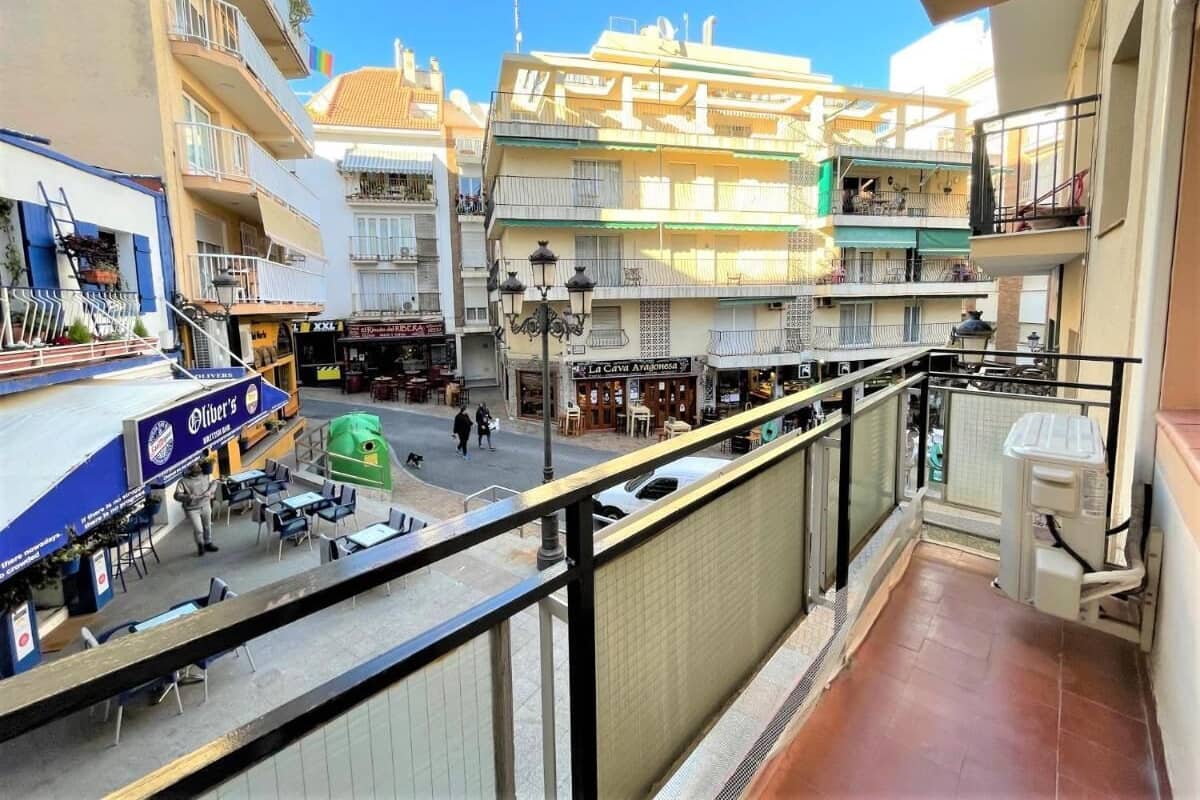 A balcony with a view of a street, outdoor seating area, and a restaurant.