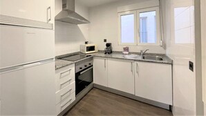 A compact kitchen with white cabinets, a microwave, a coffee maker, and a stove. - L&G Apartamentos (Benidorm)