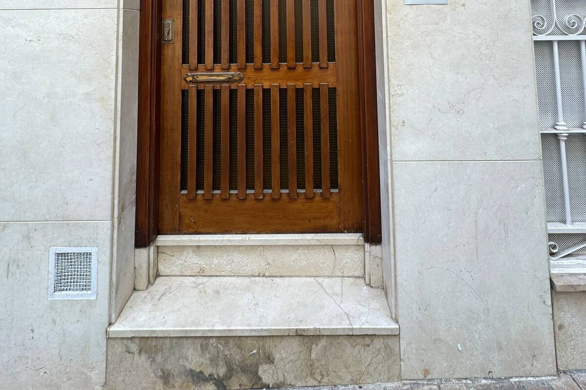 A wooden door with vertical bars, a number plate '25', and a sign indicating a video surveillance zone.