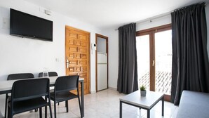 A modern room with a dining table, chairs, a TV, a small table with a plant, and a sofa. - L&G Apartamentos (Benidorm)