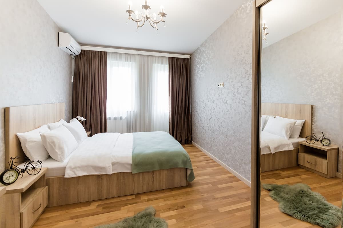 A modern bedroom with a wooden bed, a mirror, a bicycle, and a green rug.