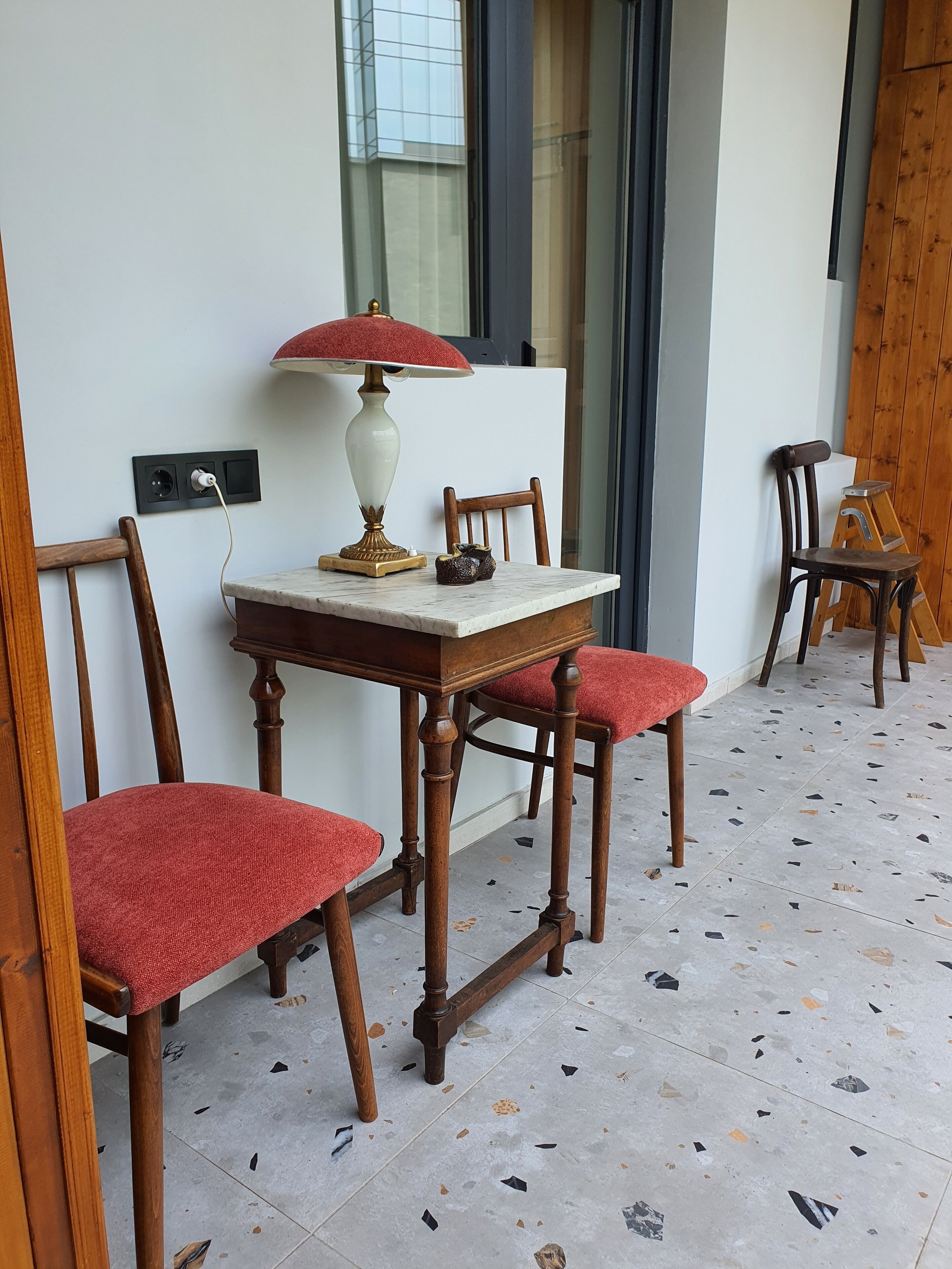 Un coin repas avec une table et des chaises en bois, une lampe et une prise électrique au mur.