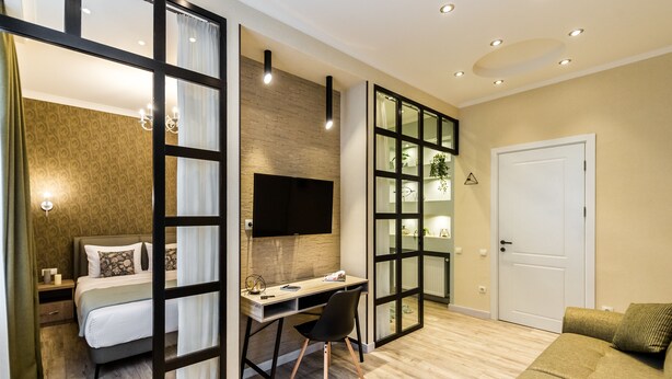 Een moderne hotelkamer met een bed, bureau, stoel en een televisie.