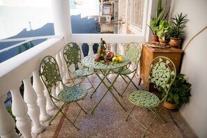 A balcony with a round table, four chairs, and potted plants. - Dat Exx on Freedom Square (Tbilisi)