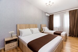 A hotel room with two beds, a nightstand with a lamp, and a window with curtains. - Dat Exx on Freedom Square (Tbilisi)