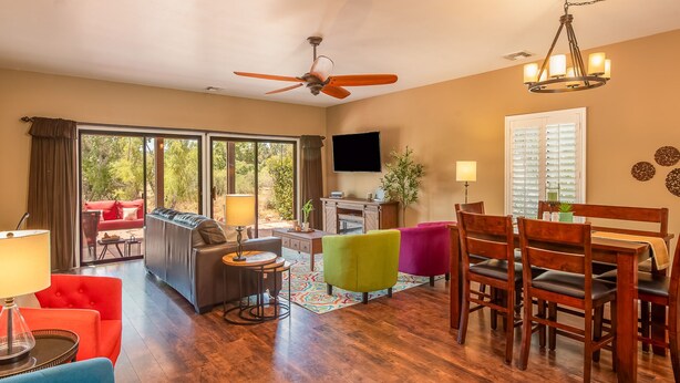 A spacious living area with a ceiling fan, a dining table with chairs, a sofa, and a television. - Private Home with Courtyard, Walk to Trails & Dining, Pets Welcome! (Sedona)